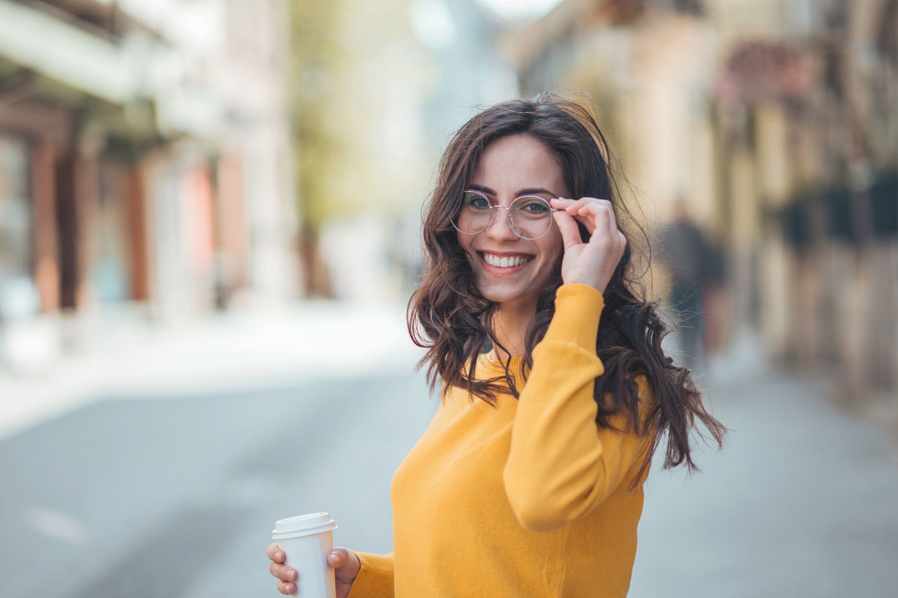 Happy girl wearing yellow sweater and black framed eyeglasses- Total Vision and Hearing in Ancaster, Ontario
